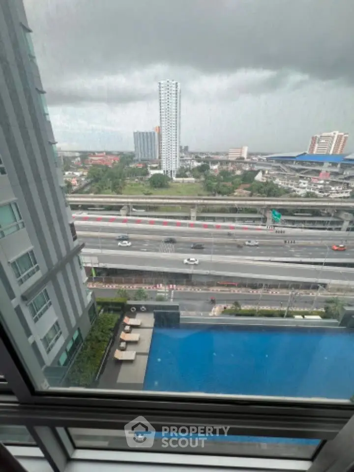 High-rise building view with pool and cityscape from window, showcasing urban living.