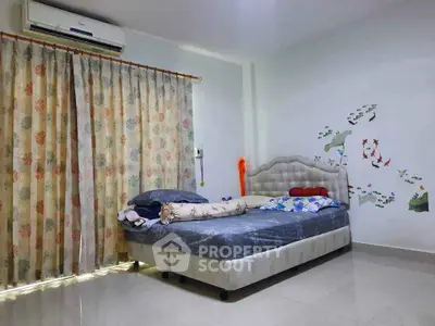 Cozy bedroom with floral curtains and wall art, featuring a comfortable bed and air conditioning.