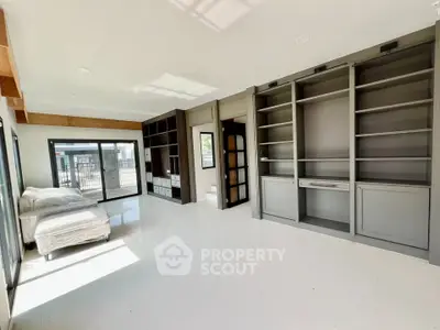 Spacious modern living room with built-in shelves and large windows offering natural light.