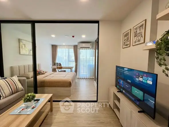 Modern apartment interior with cozy living room and stylish bedroom separated by glass partition.
