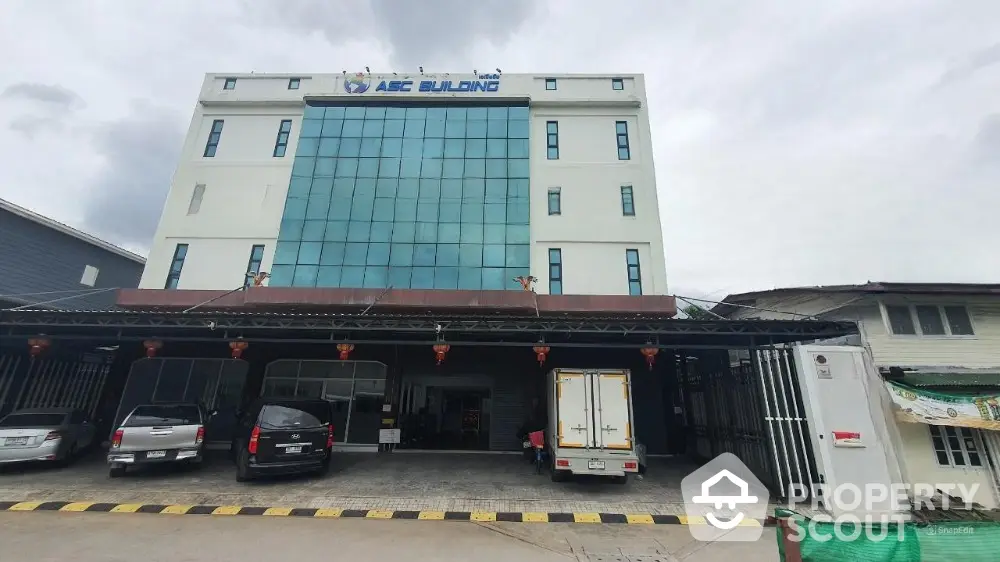 Modern commercial building with glass facade and parking area