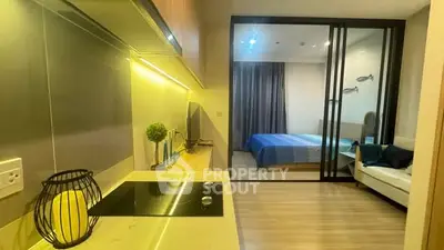 Modern apartment interior with sleek kitchen and cozy bedroom separated by glass doors.