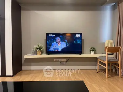 Modern living room with wall-mounted TV, stylish decor, and cozy seating area.