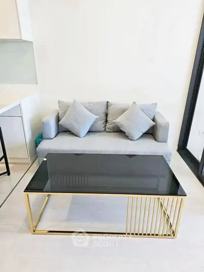 Modern living room with sleek gray sofa and stylish glass coffee table in a bright interior.