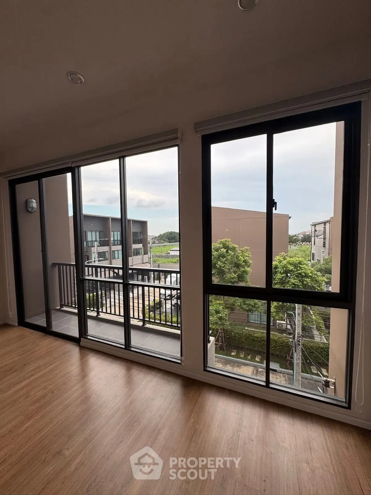 Spacious room with large windows offering a stunning view of modern architecture and greenery.