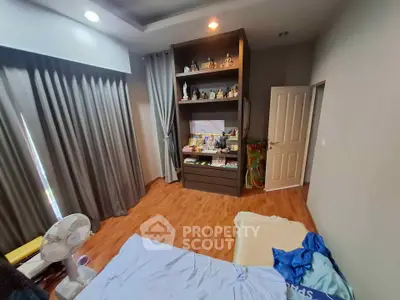 Cozy bedroom with wooden flooring and built-in shelves, perfect for a comfortable living space.