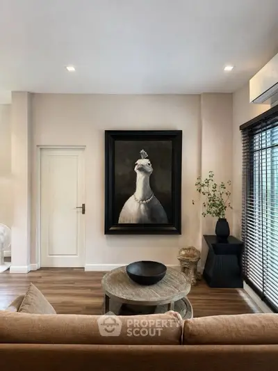 Stylish living room with elegant decor and unique peacock artwork, featuring modern furniture and natural light.