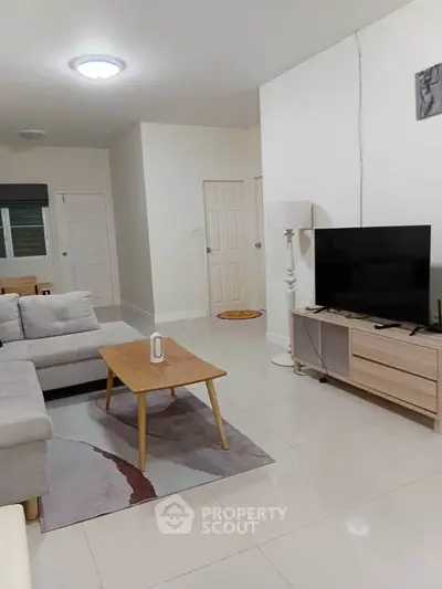 Spacious living room with modern furniture and TV, perfect for relaxation and entertainment.