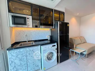Modern kitchen with marble countertops, washing machine, and sleek appliances in a cozy living space.