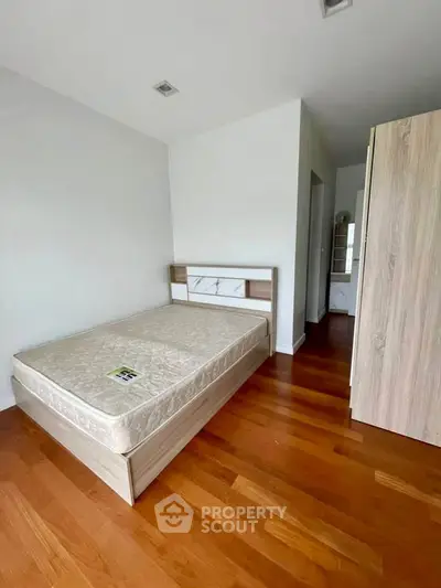 Spacious bedroom with wooden flooring and modern furnishings in a stylish apartment.