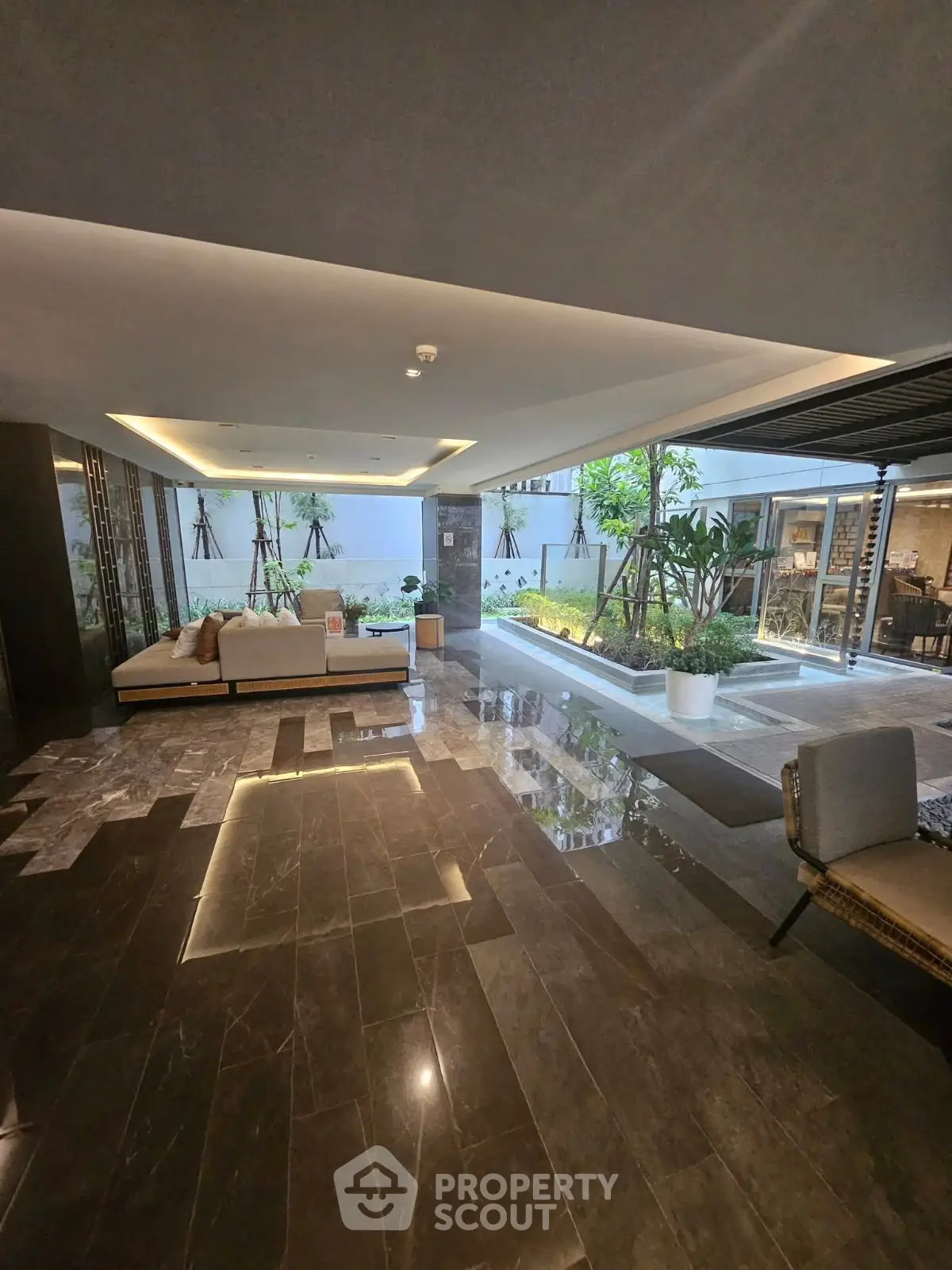 Luxurious modern building entrance with elegant seating and lush greenery