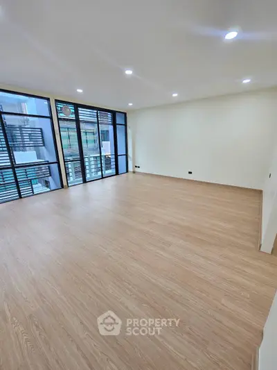 Spacious modern living room with large windows and wooden flooring