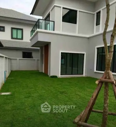 Modern two-story house with lush green lawn and large windows