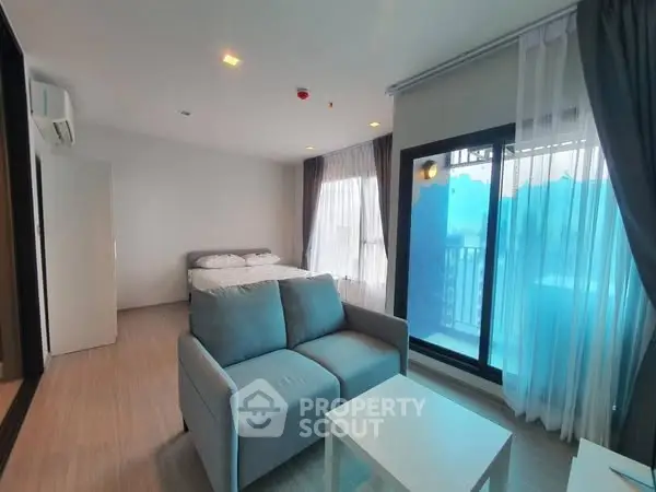 Modern studio apartment with cozy living area and balcony view