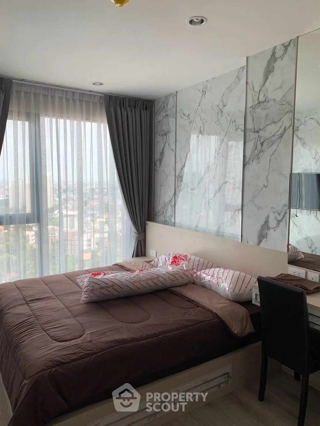 Modern bedroom with city view, featuring marble accent wall and stylish decor.