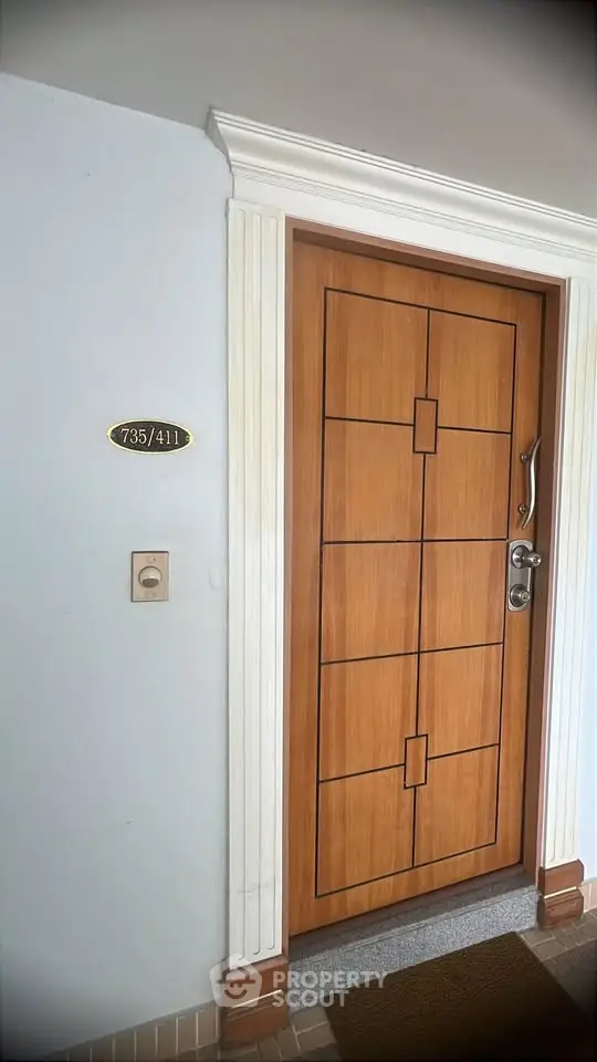 Elegant wooden apartment door with modern design and room number plaque.