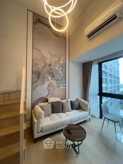 Modern living room with high ceiling, elegant decor, and large windows offering natural light.
