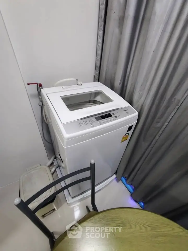 Compact laundry area with top-loading washing machine and modern decor