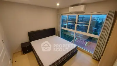 Spacious bedroom with large window offering city view and modern furnishings