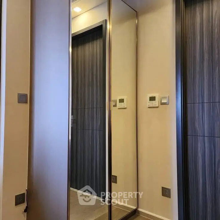 Modern hallway with mirrored closet doors and sleek wooden accents.