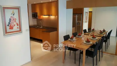 Modern dining area with elegant table setting and adjacent sleek kitchen in open layout apartment.