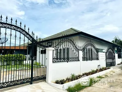 Charming single-story home with elegant wrought iron fence and lush greenery