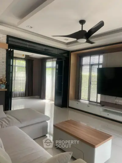 Spacious modern living room with sleek ceiling fan and large windows for natural light.