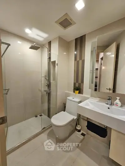 Modern bathroom with glass shower, sleek fixtures, and elegant tile design.