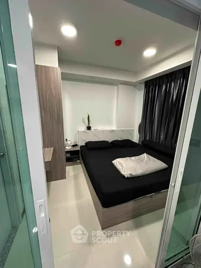 Modern bedroom with sleek design and black bedding in a contemporary apartment.