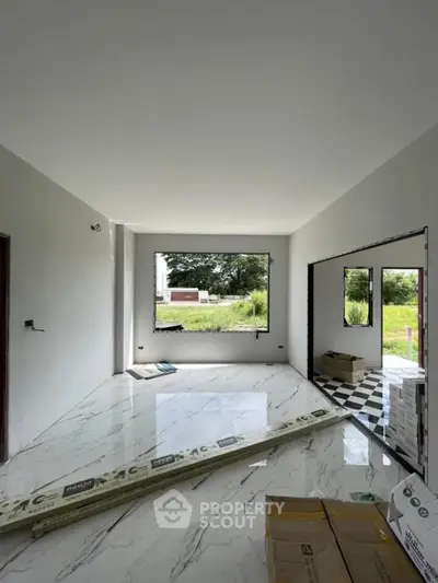 Spacious modern living room with large window and marble flooring under construction.