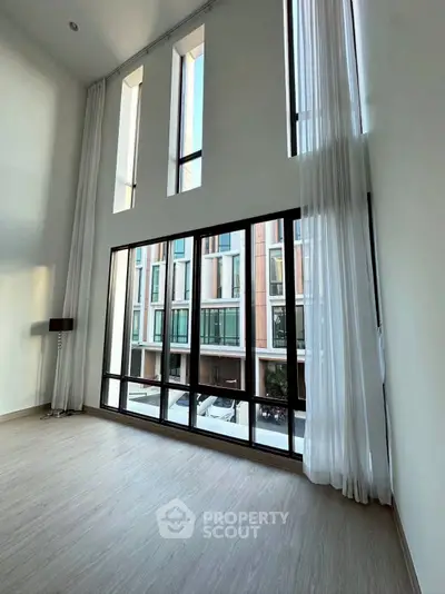 Spacious modern living room with floor-to-ceiling windows and elegant curtains