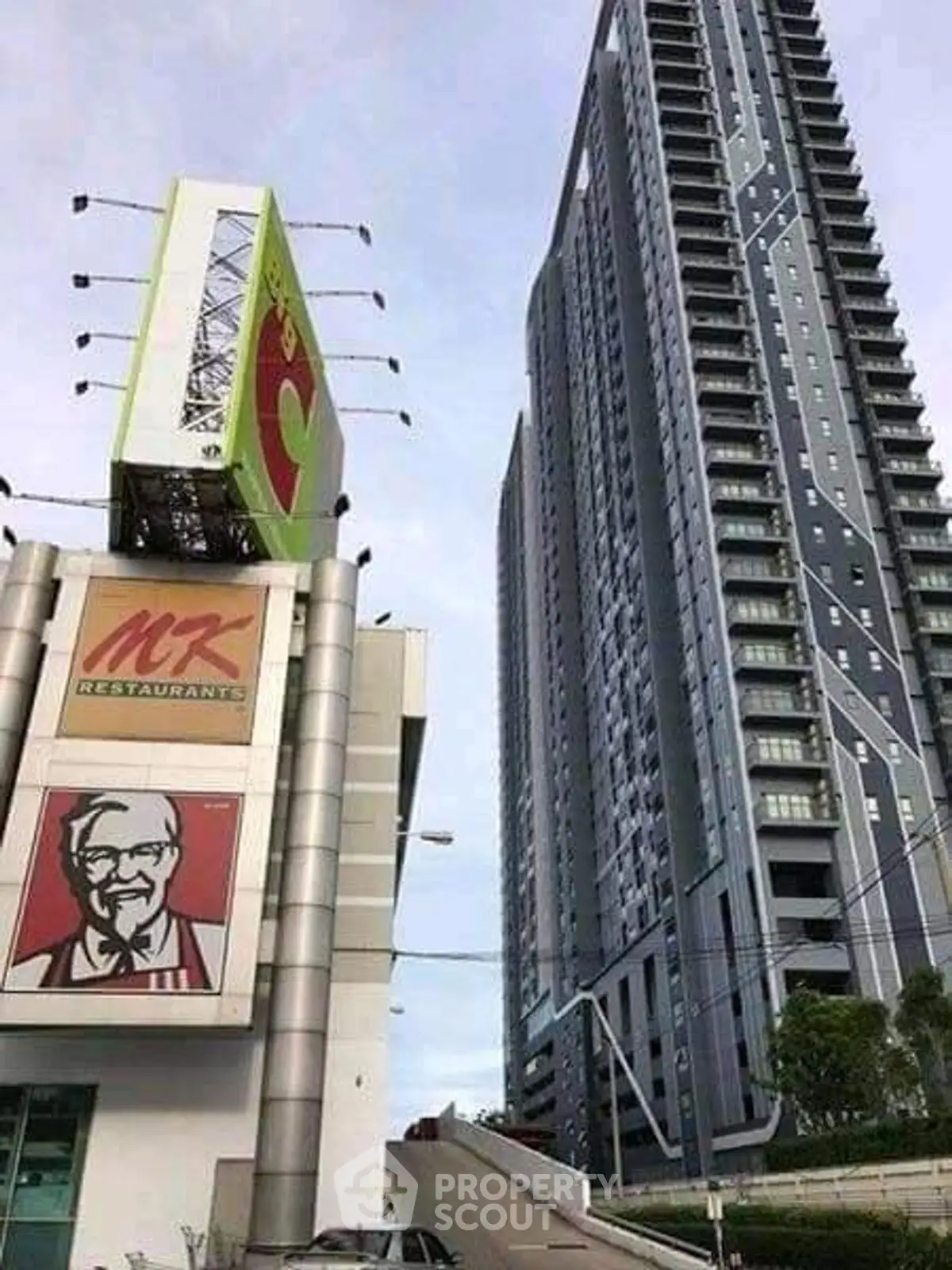 Modern high-rise building with adjacent commercial signage in urban setting.
