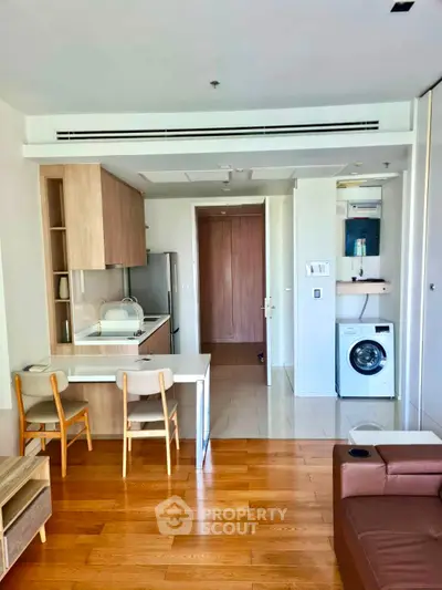 Modern open-layout kitchen with wooden flooring and built-in appliances in a stylish apartment.
