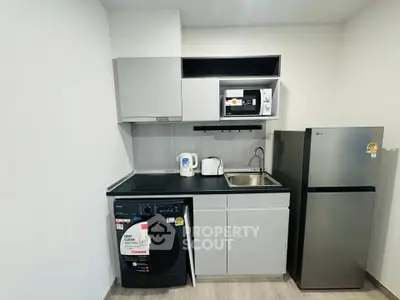 Modern compact kitchen with appliances including fridge, microwave, and washing machine.