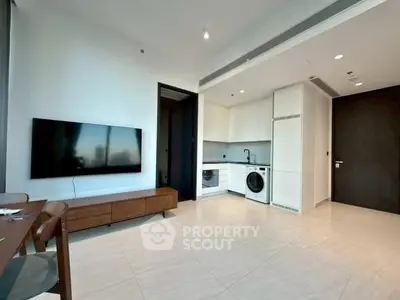 Modern living room with sleek kitchen, TV, and washing machine in open layout.