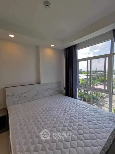 Bright bedroom with large window and modern decor in a stylish apartment.