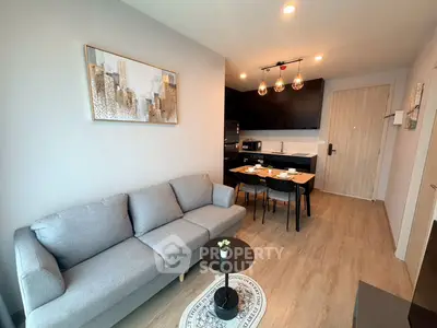 Modern living room with cozy gray sofa and stylish kitchen in open layout apartment.
