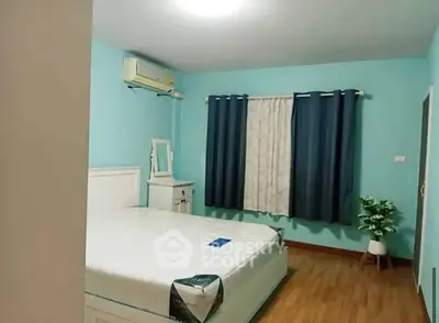 Cozy bedroom with blue walls, white furniture, and wooden flooring.