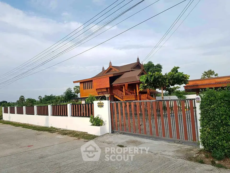 Charming traditional wooden house with lush greenery and secure gated entrance, perfect for serene living.