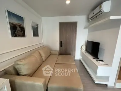Modern living room with beige sofa, wall-mounted TV, and air conditioning unit.