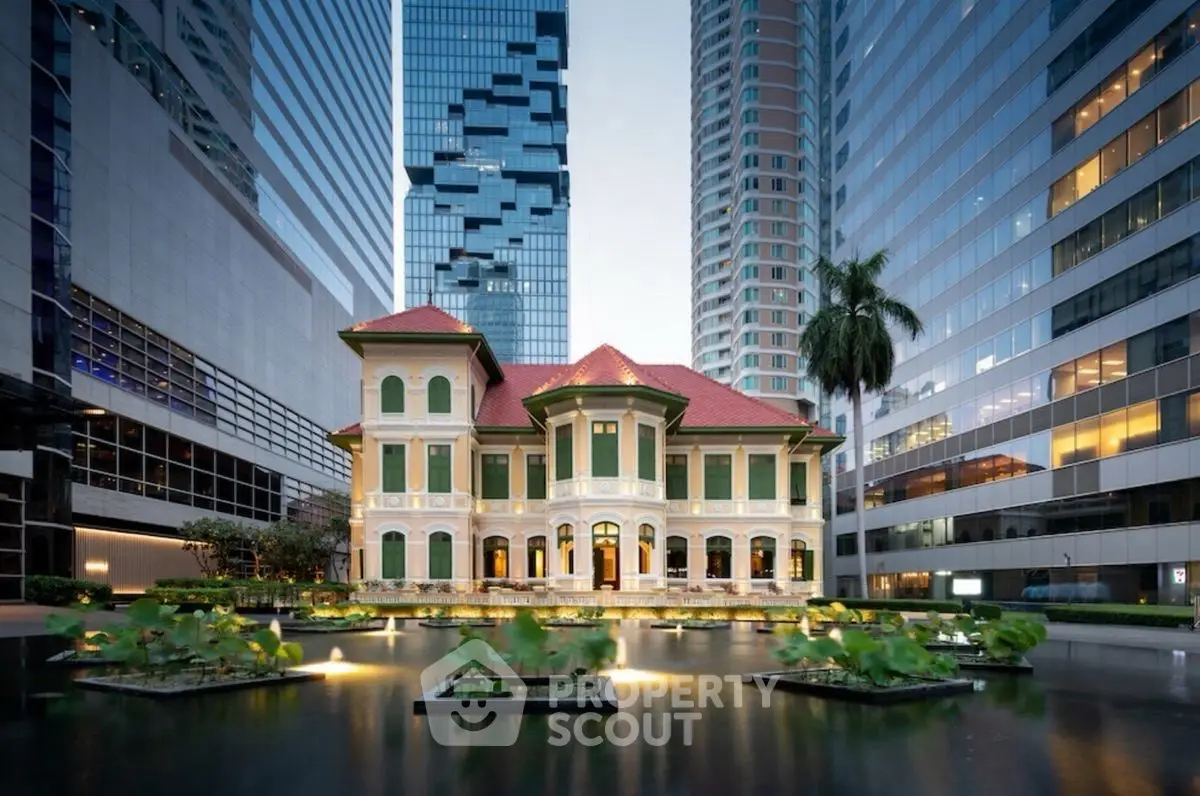 Stunning historic building amidst modern skyscrapers with serene water feature.