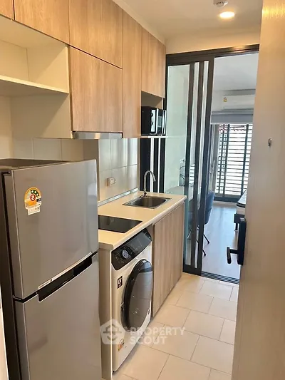 Modern compact kitchen with washing machine and fridge in sleek apartment