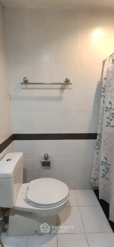 Modern bathroom with white tiles and shower curtain in a real estate property.