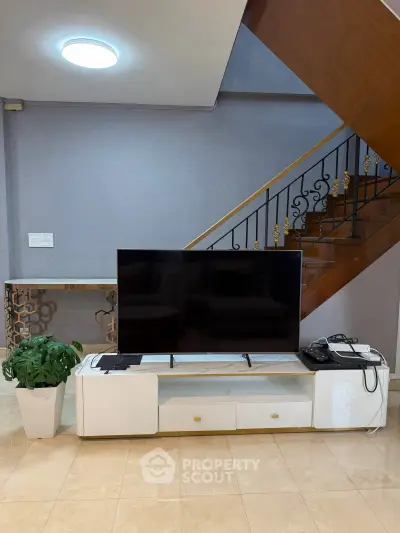 Modern living room with sleek TV stand and elegant staircase, perfect for stylish home entertainment.