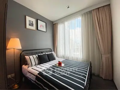 Cozy modern bedroom with stylish decor and large window for natural light.