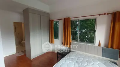 Bright bedroom with large window and wooden flooring, featuring a built-in wardrobe and ensuite bathroom.