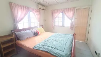 Cozy bedroom with natural light, featuring a comfortable bed and soft pink curtains.