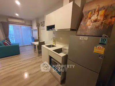 Modern open-layout living room with kitchen, featuring sleek appliances and stylish decor.
