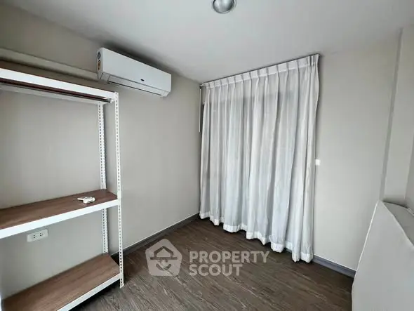Minimalist room with air conditioning and wooden flooring, ideal for a cozy living space.