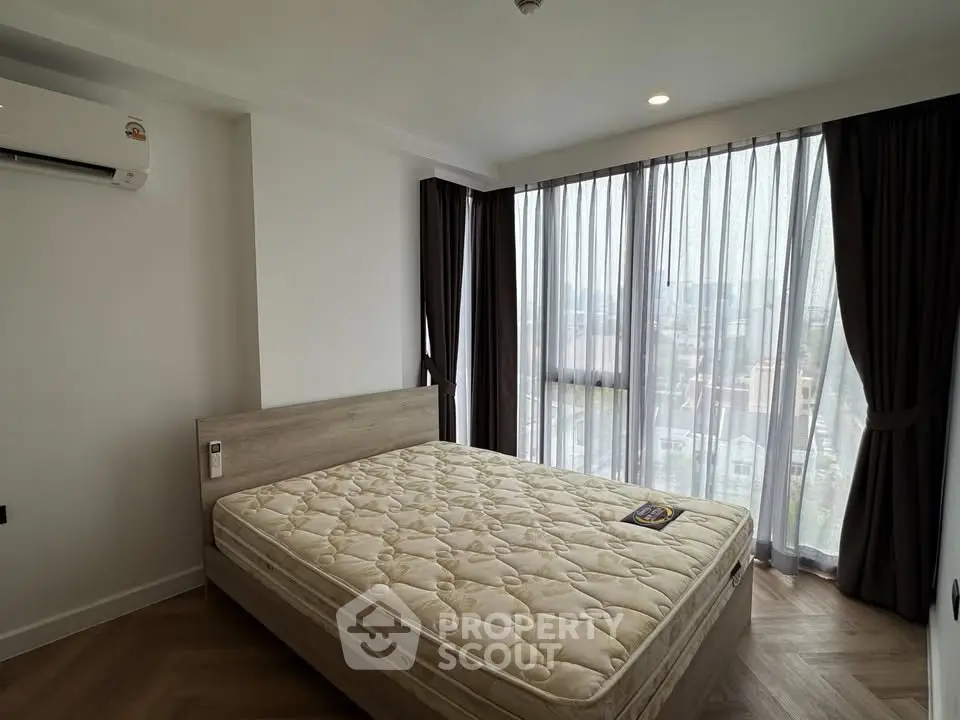 Modern bedroom with large windows and natural light, featuring a comfortable bed and stylish decor.